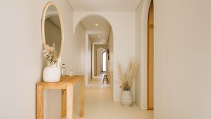 A hallway with a wooden bench, a large mirror, and a vase with dried flowers. - Ando Living - Comporta Villas - Villa 11 (Carvalhal)