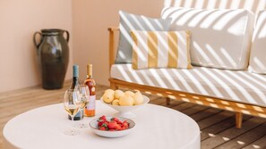 Ein runder Tisch mit einer weißen Schale Erdbeeren, einer Zitronenschale, zwei Weinflaschen und zwei Weingläsern.