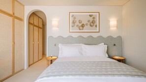 Habitación de hotel con cama, dos mesitas de noche, cabecera, armario y un cuadro en la pared.