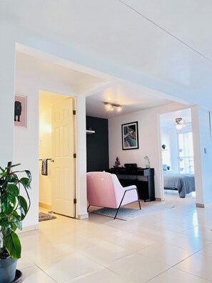 A modern living room with a white door, a pink chair, a black desk, and a ceiling fan. - Becerra Apartments (Ciudad de México)