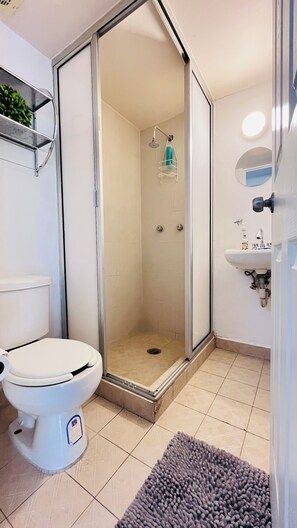 A bathroom with a toilet, a shower enclosure, and a sink. - Becerra Apartments (Ciudad de México)