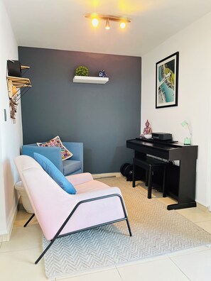 A modern living room with a sofa, a chair, a desk, and a wall-mounted shelf with decorative items. - Becerra Apartments (Ciudad de México)
