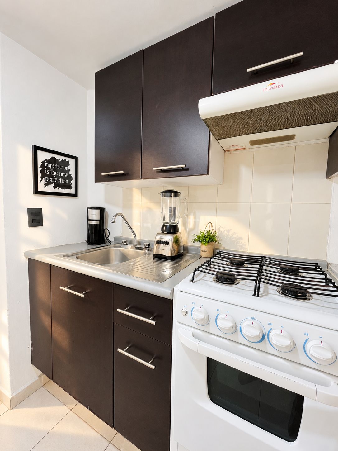 A modern kitchen with dark cabinets, a white countertop, a stove with four burners, and a built-in oven.