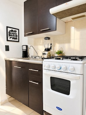 Una cocina compacta con estufa, horno y cafetera.