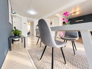 A modern dining area with a grey upholstered chair, a white table, and a grey rug. - Becerra Apartments (Ciudad de México)