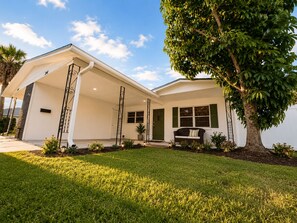 A single-story house with a covered porch, a large tree in front, and a well-maintained lawn. - Aroma Escape 🌴 Private Hot Tub • Near Beaches • Pet-Friendly (Bradenton)