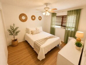 A bedroom with a bed, a ceiling fan, a potted plant, and a bedside table with a lamp. - Aroma Escape 🌴 Private Hot Tub • Near Beaches • Pet-Friendly (Bradenton)