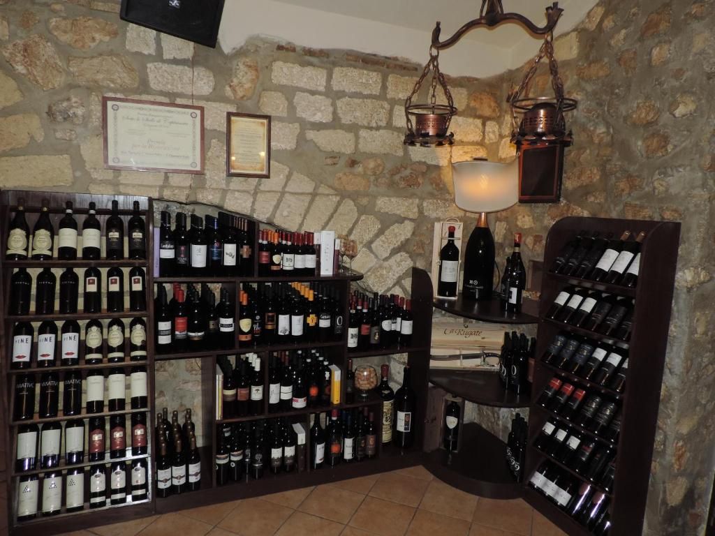 A wine cellar with shelves of wine bottles, a stone wall, and hanging lanterns.