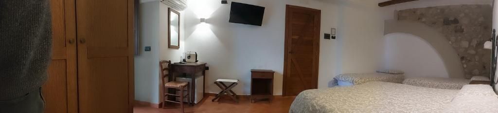 Ein Zimmer mit einem Bett, einem Schreibtisch, einem Sessel, einem Fernseher und einer Steinsäule.