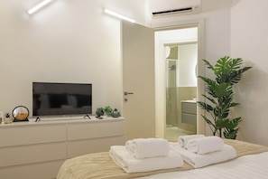A hotel room with a bed, a television, a bathroom with a shower, and a potted plant. - Executive Suite Nirone 8 (Milano)
