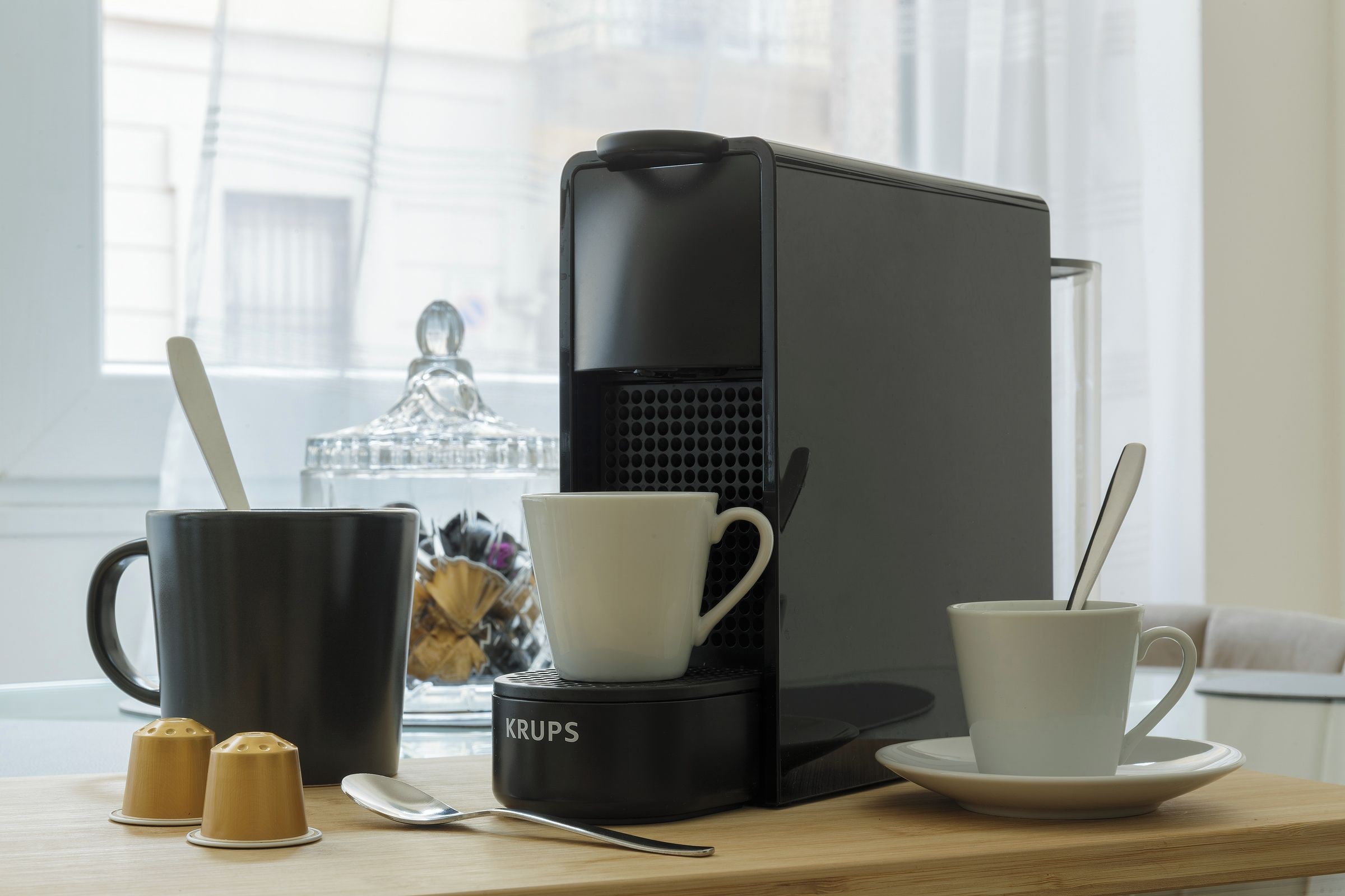Una moka su un tavolo con due tazze e cubetti di zucchero.