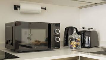 Una kitchenette con horno tostador 3DWave, cafetera y tarro de vidrio con objetos decorativos.