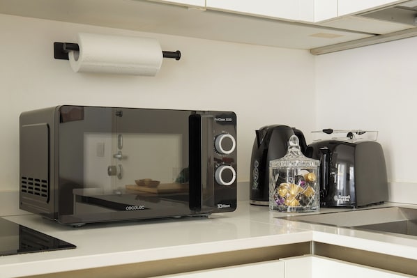 Una kitchenette con horno tostador 3DWave, cafetera y tarro de vidrio con objetos decorativos.