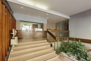 Ein modernes Interieur mit Treppe, Holzvertäfelung und einer Rezeption.