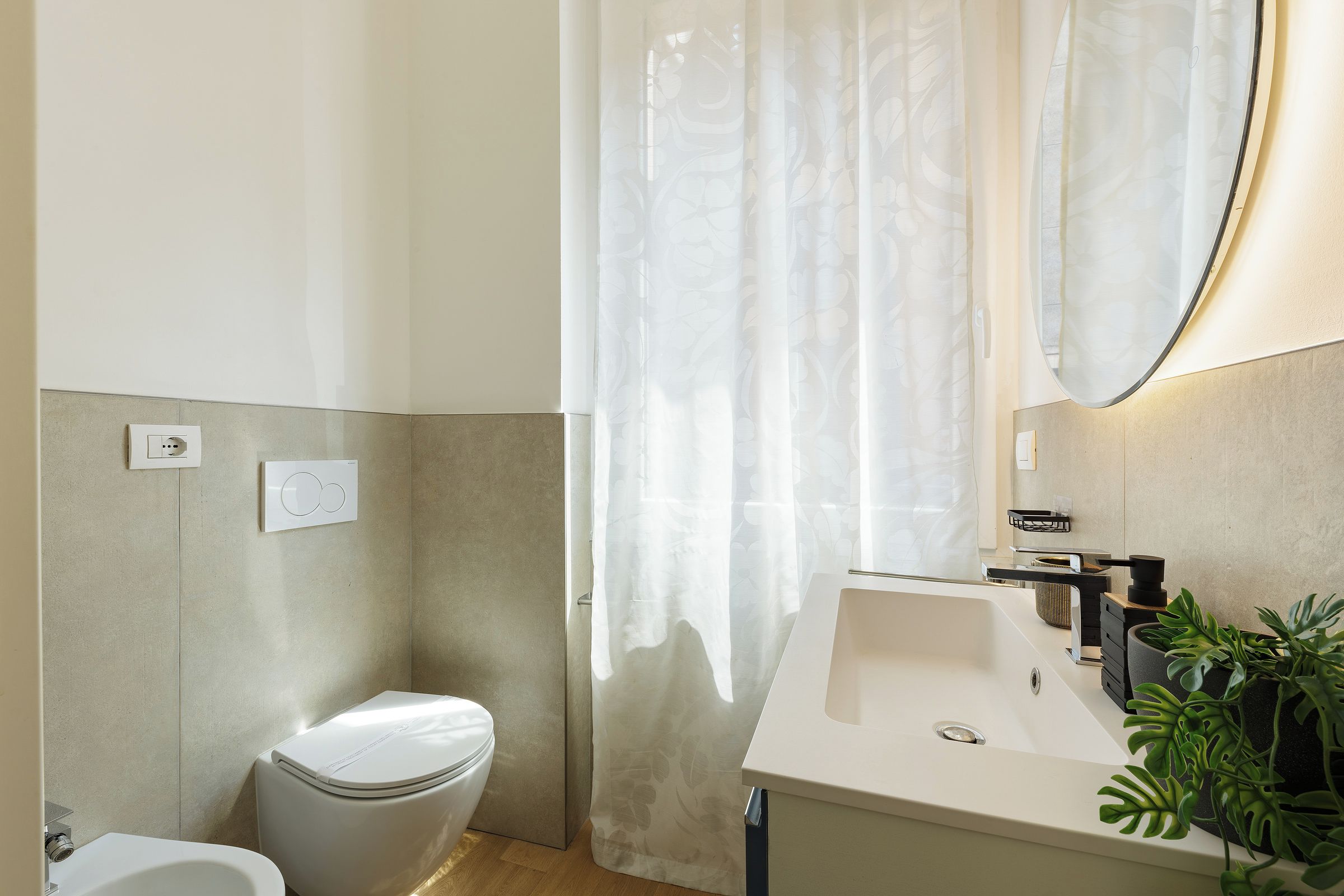 A modern bathroom with a toilet, sink, and shower curtain.