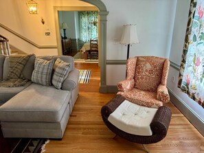 A living room with a grey sofa, a patterned armchair, and a wooden floor. - Camden at Monticello (Salisbury)
