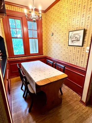 A dining area with a wooden table and chairs, a chandelier, and patterned wallpaper. - Camden at Monticello (Salisbury)