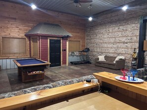 Una habitación con mesa de billar, cinta de correr, sofá y banco de madera.