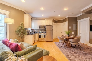 A modern kitchen with white cabinets, stainless steel appliances, and a dining area with a wooden table and chairs. - Cambridge Cozy Home ,3bedroom/2bath ,Sleeps 8 (Cambridge)