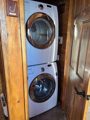 A compact, two-door laundry room with a wooden door and a white washing machine. - Newly Renovated Cottage Stoney Lake (Douro-Dummer)