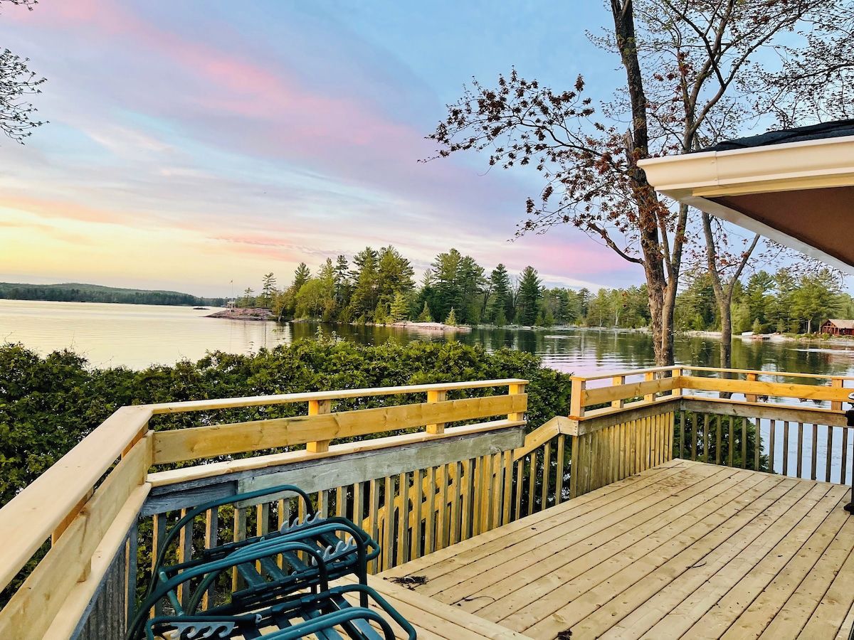A wooden deck with a view of a lake and trees.