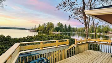 A wooden deck with a view of a lake and trees.
