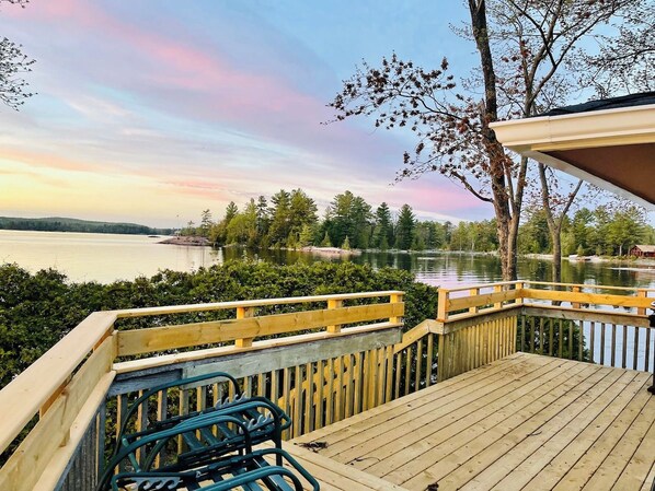 Una terraza de madera con vistas a un lago y árboles.