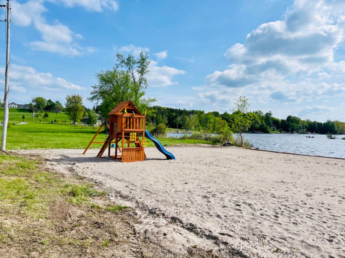 A sandy beach with a wooden play structure and a slide.
