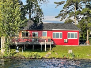 A red house with a balcony, a dock, and a grassy yard. - Newly Renovated Cottage Stoney Lake (Douro-Dummer)