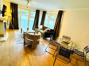 A furnished living room with a sofa, armchairs, a coffee table, and a dining table with chairs. - Modern Finnieston 2 Bed Apt, near SEC & OVO, Free Parking (Glasgow)