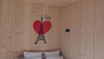 Een kamer met houten lambrisering, een bed, een wandlamp en een Parijs-thema, inclusief de Eiffeltoren en een hart.