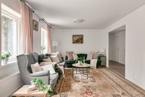 Un salon comprenant un canapé, des fauteuils, une table basse et un tapis à motifs.