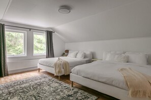 A bedroom with two beds, a window, a radiator, and a patterned rug. - Brand new house near lake and public transport (Huddinge)