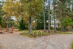 Un parc avec un sentier de gravier, des poteaux en métal et un pont en bois.