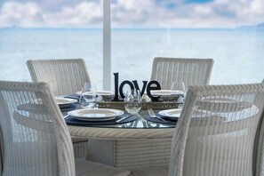A table set for four with a view of the sea, a 'love' centerpiece, and wicker chairs. - Hampton Cottage by the Lake - Taupo Holiday Home (Taupo)