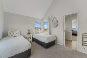 Ein Schlafzimmer mit zwei Betten, einem Nachttisch, einem Spiegel und Blick ins Freie.