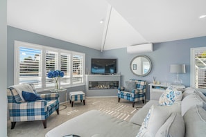 A living room with a fireplace, a television, and a seating area with a sofa and chairs. - Hampton Cottage by the Lake - Taupo Holiday Home (Taupo)