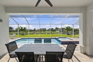 Un espace extérieur abrité comprenant une piscine, une table et des chaises.