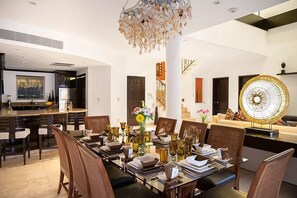 A modern dining area with a long table set for a meal, surrounded by chairs. - Two-Story Penthouse Loft, 3-bdrm Beachfront at Villa del Palmar Luxury Resort (Cancun)