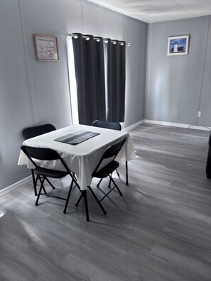 A dining area with a table, chairs, and a window with curtains. - Beautiful 3-bedroom mobile home with AC in Port Orange (Port Orange)