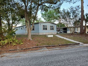 A single-story house with a front porch, a small yard, and a driveway. - Beautiful 3-bedroom mobile home with AC in Port Orange (Port Orange)