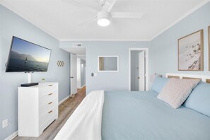 Ein Schlafzimmer mit einem Bett, einem Fernseher, einer Kommode und einem Deckenventilator.