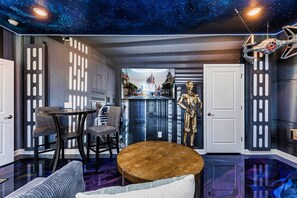 A room with a starry ceiling, a large screen displaying a castle scene, and a golden robot figure. - Sleeps 24 - Pool-Game Room-Disney-Cinema Room (Davenport)