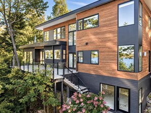 Een modern meerlaags huis met grote ramen, een balkon en een stenen fundering.