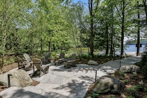 A lakeside seating area with Adirondack chairs and a concrete path. - Modern Muskoka made for Entertaining (Nipissing South (Utterson))