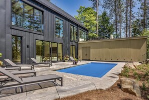 A modern house with a large glass window, a swimming pool, and outdoor furniture. - Modern Muskoka made for Entertaining (Nipissing South (Utterson))