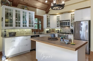 A modern kitchen with white cabinetry, a central island, stainless steel appliances, and a wooden ceiling. - Classic Cottage Living on Muldrew Lake - 4 bedroom, 3 bath (Parry Sound Mid-Shore (Bala))