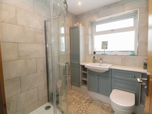 A bathroom with a glass-enclosed shower, a sink, a toilet, and a window above the mirror. - Hillset View (Bakewell)