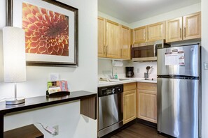 Una cocina moderna con armarios de madera, electrodomésticos de acero inoxidable y una obra de arte floral enmarcada en la pared.