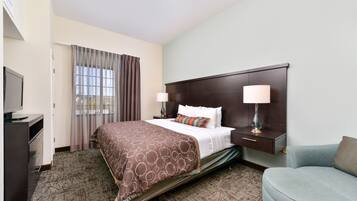 A hotel room with a bed, bedside tables, a TV, a desk, and a chair.